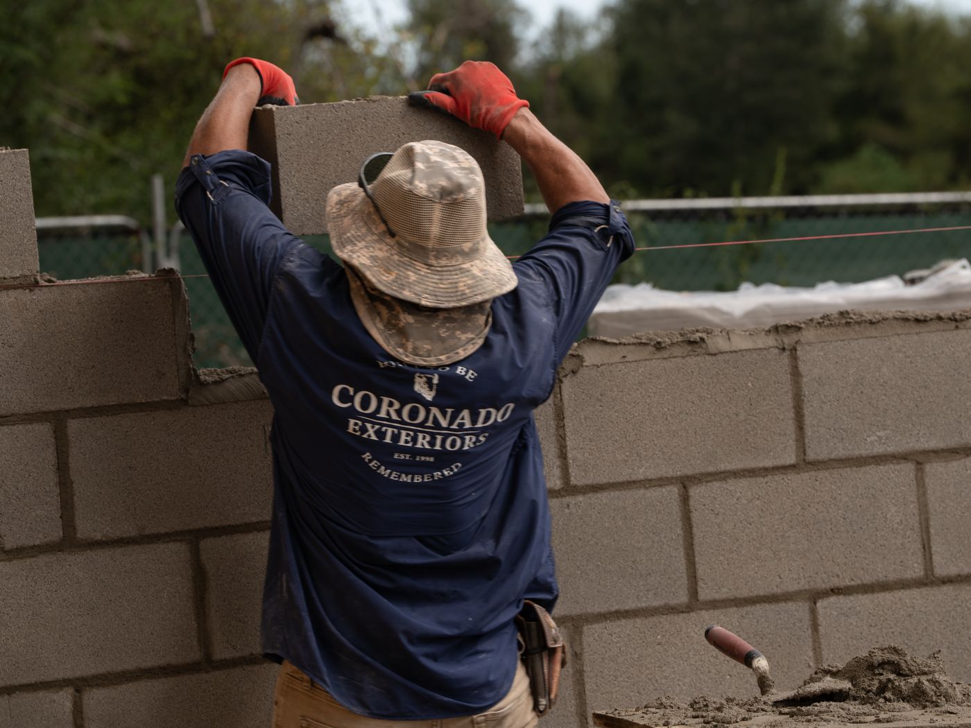 Coronado Exteriors mason setting a CMU block on a Houston block wall
