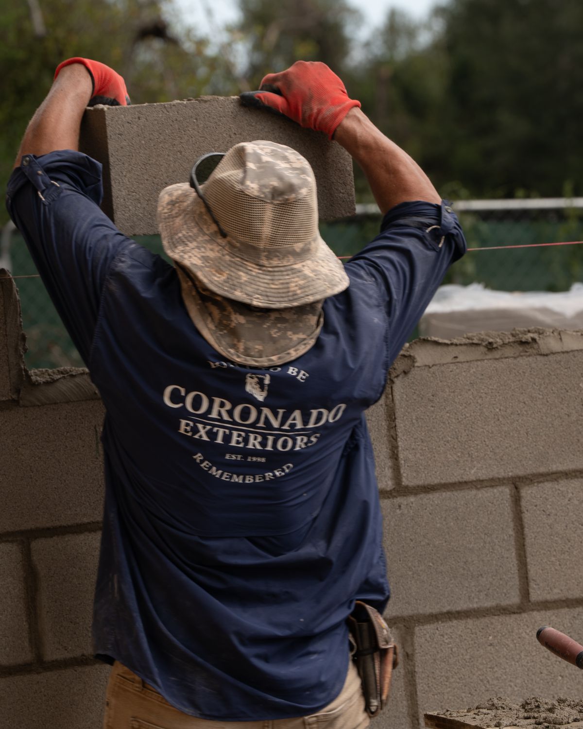 Mason lifting a concrete block onto a CMU wall in Houston, TX