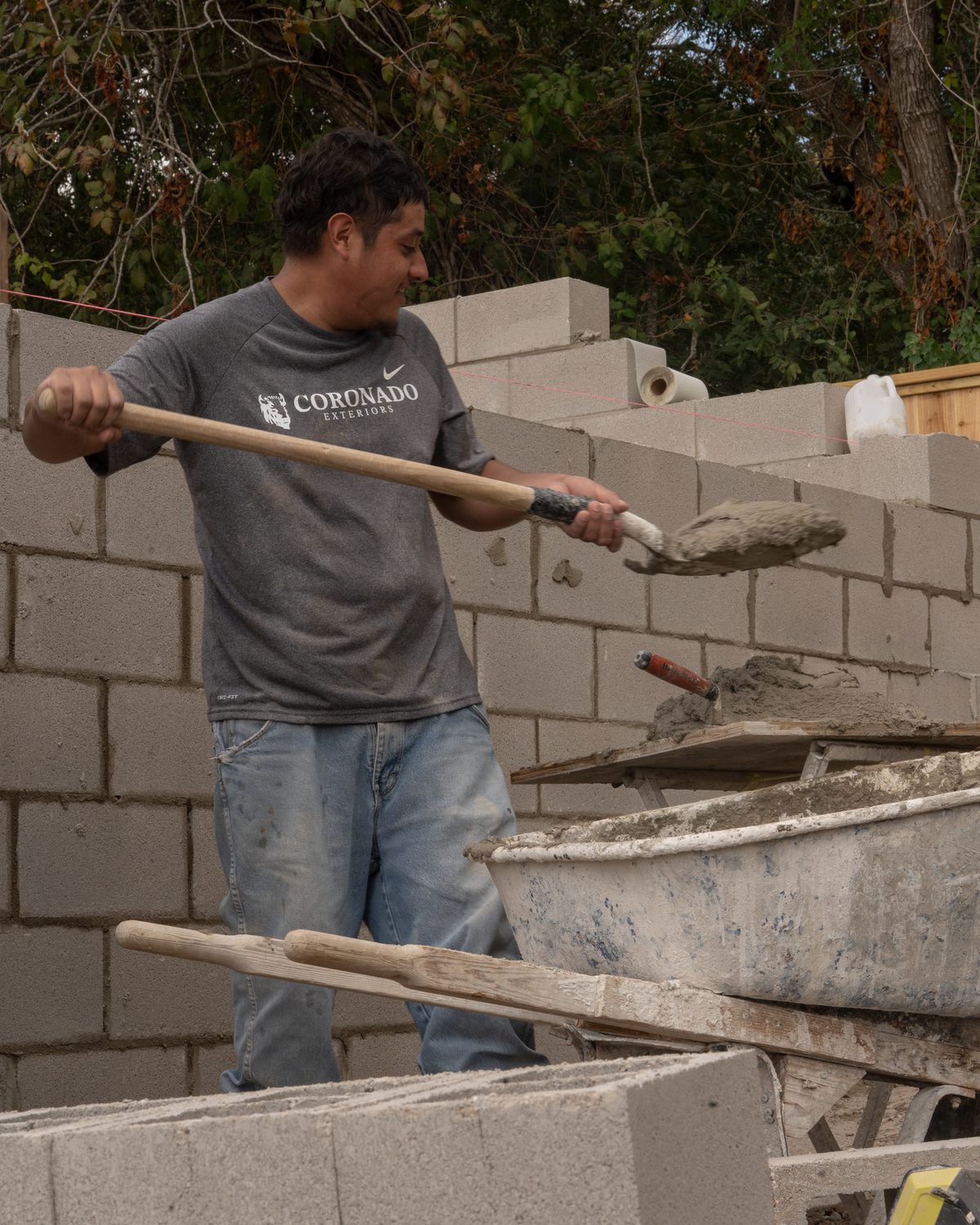 Mason loading mortar from a wheelbarrow for a CMU wall in Houston