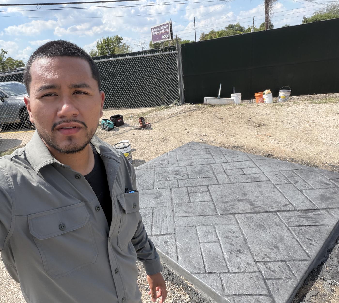 Alejandro Coronado beside a freshly sealed charcoal ashlar slate stamped concrete slab