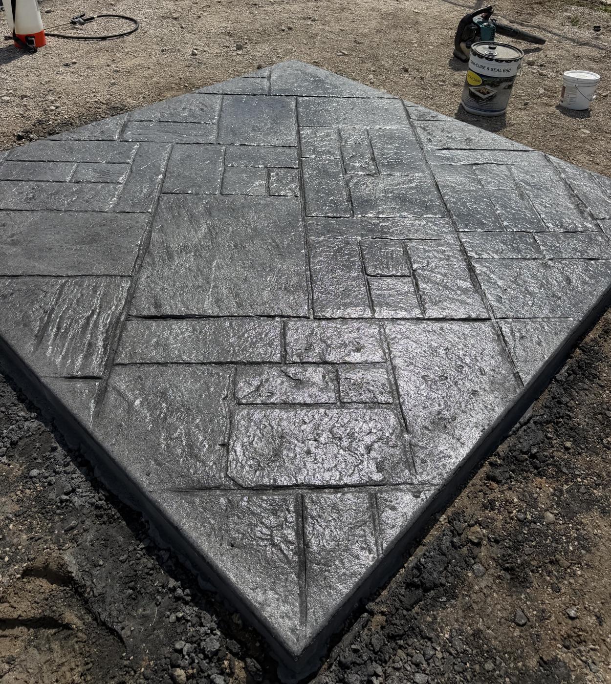 Charcoal gray ashlar slate stamped concrete slab with a glossy sealer by Coronado Exteriors